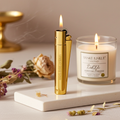Gold lighter and Yankee Candle on a marble surface with flowers and books in the background