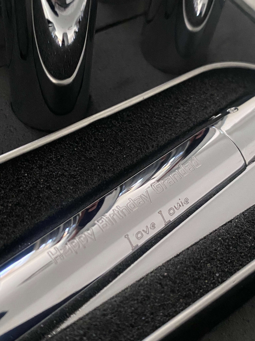 Close-up of a chrome clipper lighter with 'Happy Birthday Grandad' engraved.
