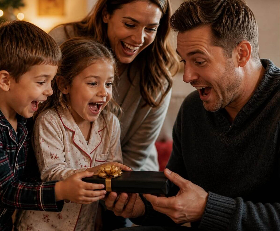 Family opening a gift together in front of a Christmas tree full of joy