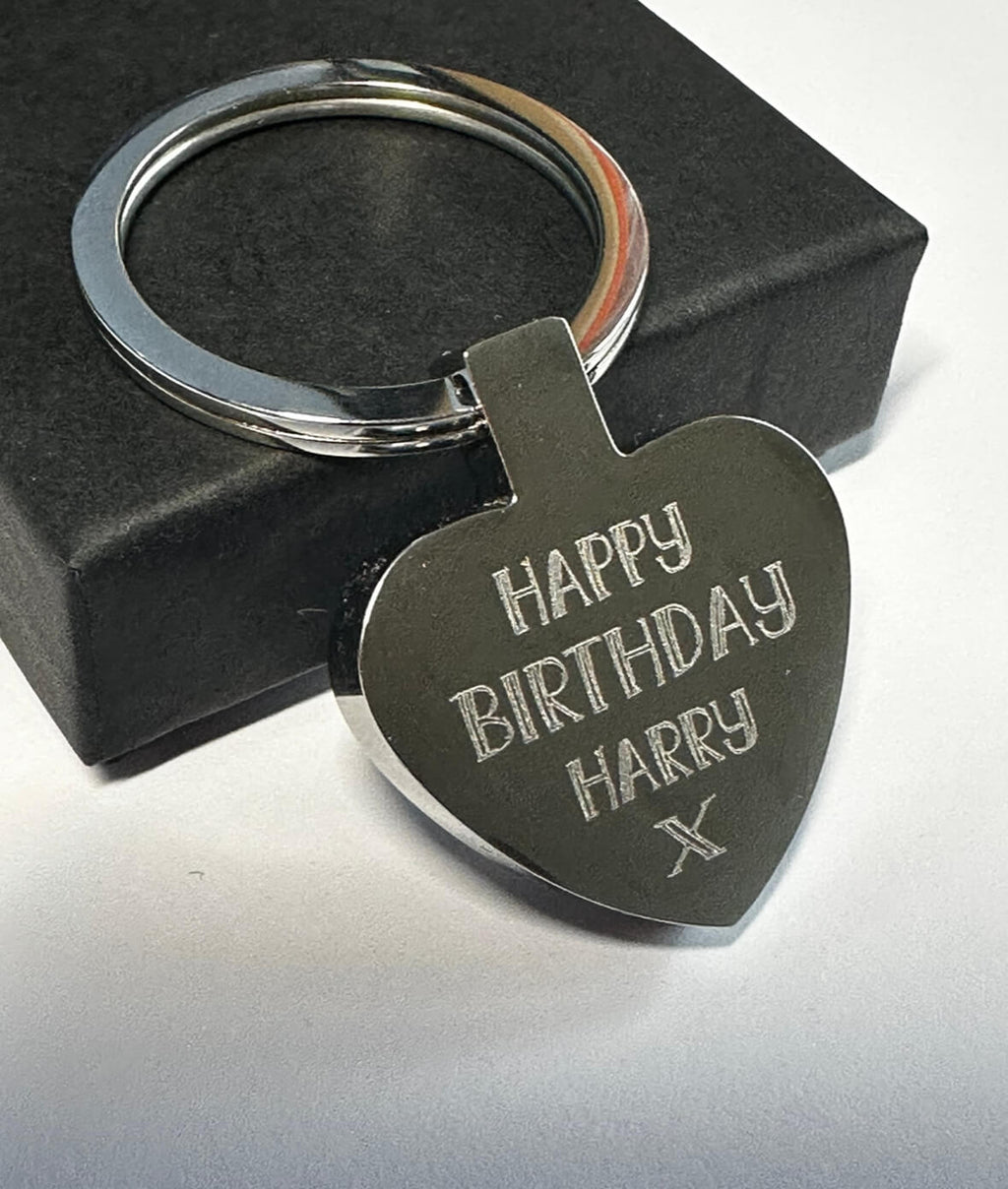 Heart-shaped keychain with 'Happy Birthday Harry' engraving on a black box background
