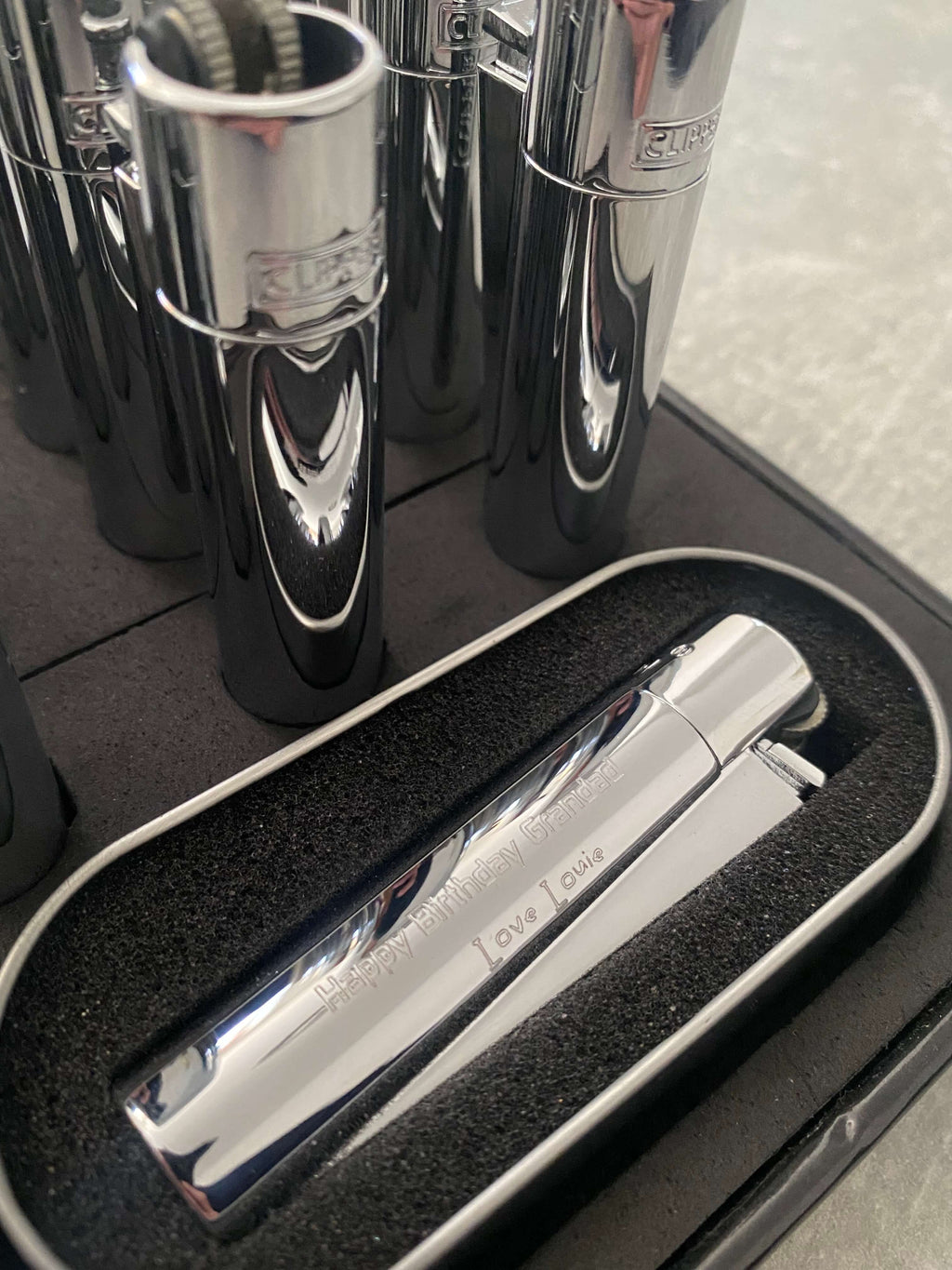 Close up of a chrome clipper lighter  with 'Happy Birthday Grandad' engraved on  