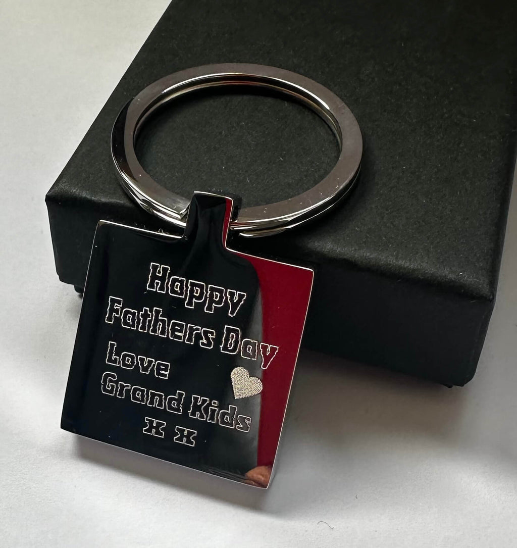 Keychain with 'Happy Fathers Day Love Grand Kids' text on a black background